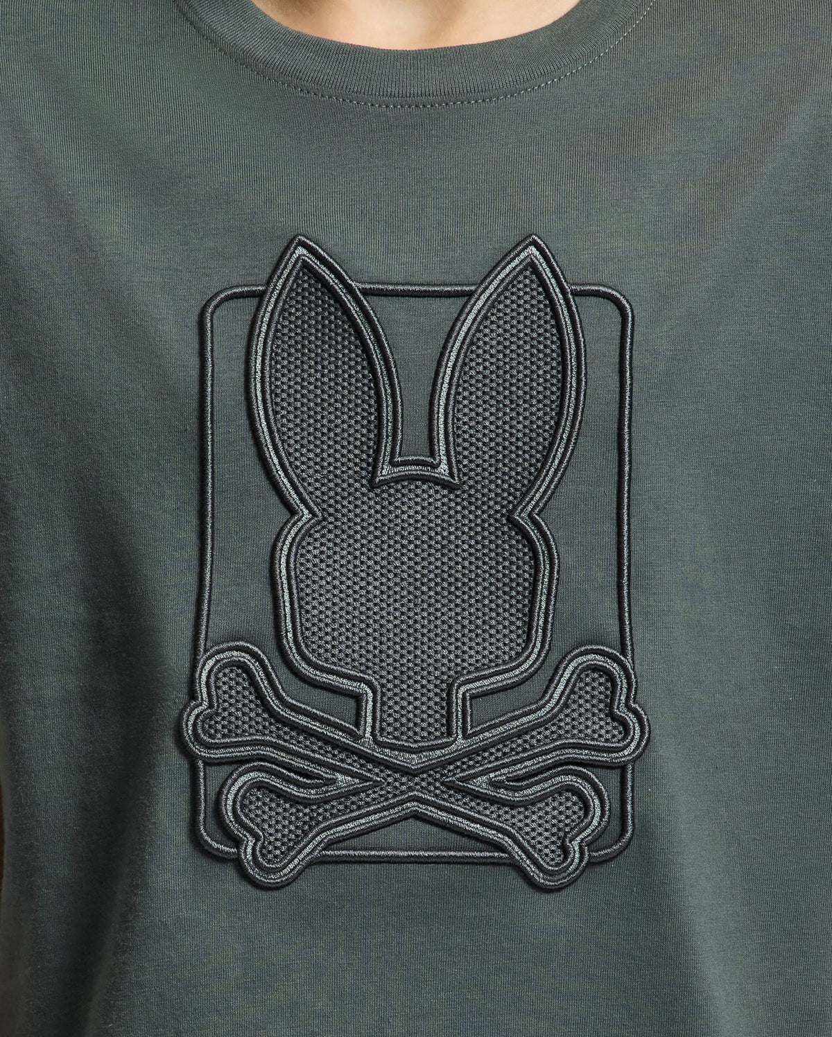 Dark green KIDS PIERCE GRAPHIC TEE by Psycho Bunny, crafted from Pima cotton, featuring a stylish embossed design with bunny embroidery that displays a rabbit silhouette above crossed bones.