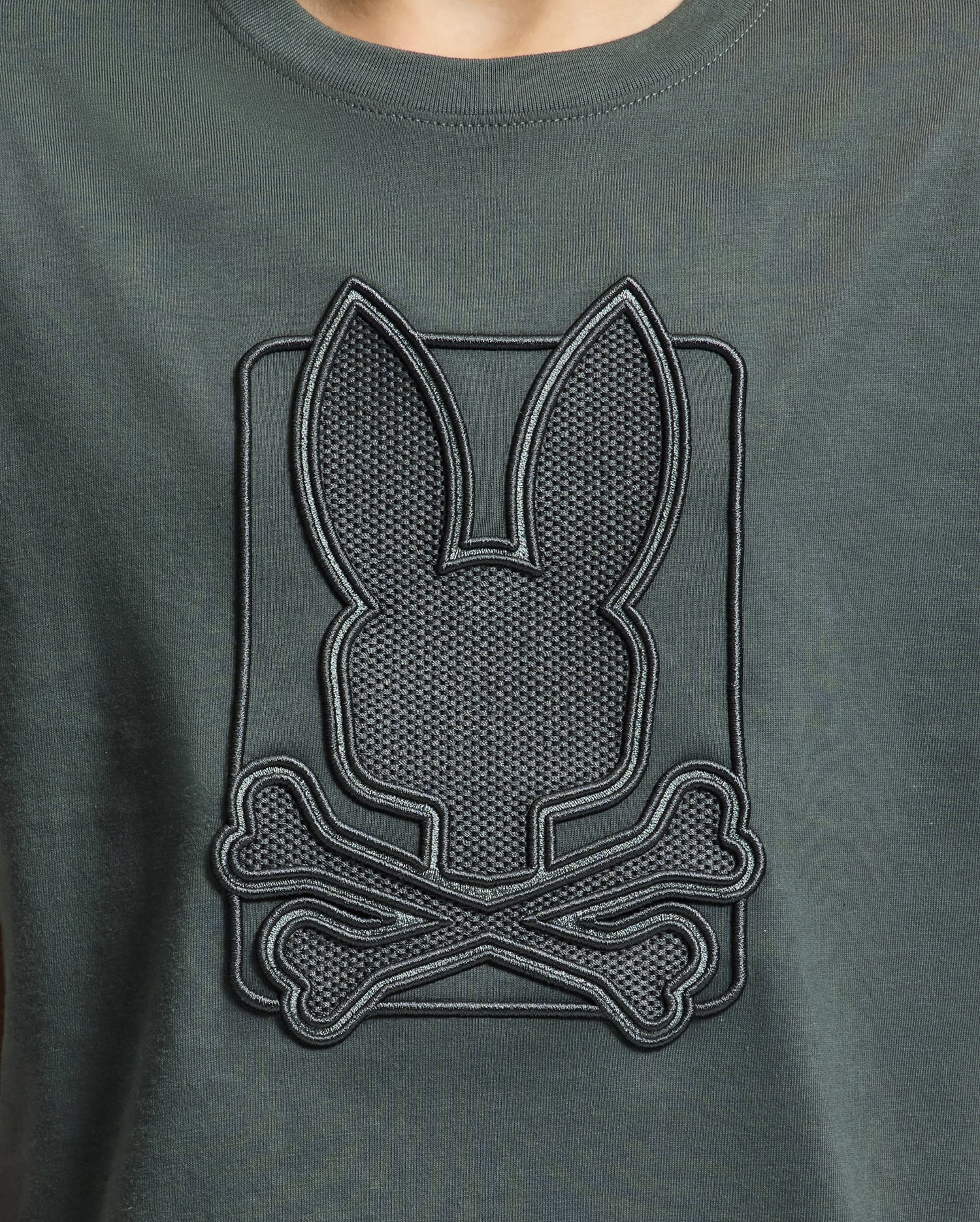Dark green KIDS PIERCE GRAPHIC TEE by Psycho Bunny, crafted from Pima cotton, featuring a stylish embossed design with bunny embroidery that displays a rabbit silhouette above crossed bones.