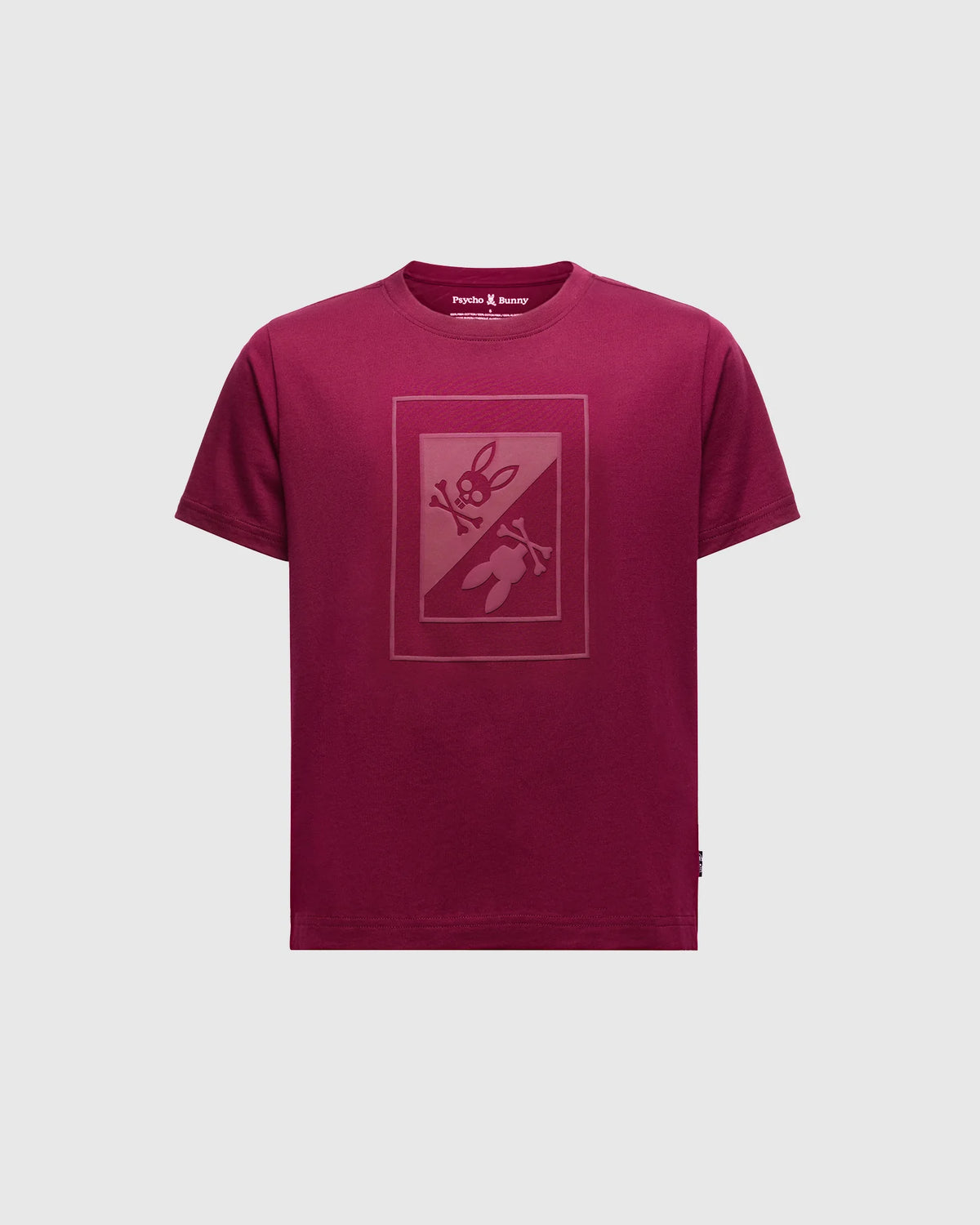The Psycho Bunny Kids Dotser Printed Graphic Tee in maroon features a subtle bunny with a carrot on the front. Crafted from soft Peruvian Pima cotton, it includes a neck label reading "Purple & Reeny.