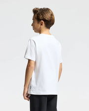 A young boy with light brown hair stands against a plain white background, wearing a Psycho Bunny KIDS MONARC WORDMARK GRAPHIC TEE - B0U210E200 made of soft Pima cotton and dark pants, facing slightly to the side.