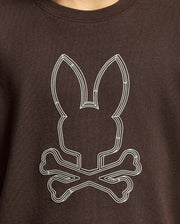 Introducing the KIDS MONARC FRONT BUNNY GRAPHIC TEE - B0U211E200 from Psycho Bunny: a stylish brown shirt crafted from luxurious Pima cotton. It showcases a unique design featuring a stylized outline of a bunny head above crossed bones in crisp white, perfectly capturing the distinctive flair of Monarc.