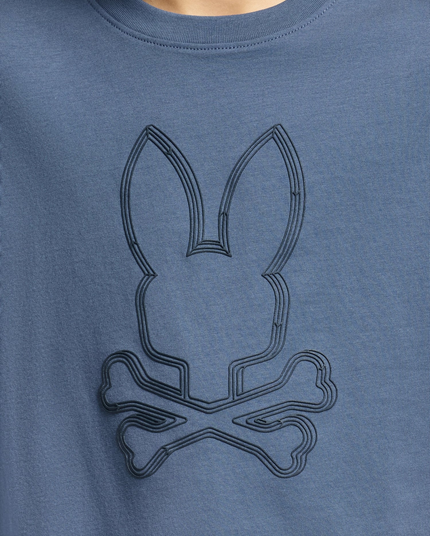 The KIDS MONARC FRONT BUNNY GRAPHIC TEE - B0U211E200 by Psycho Bunny showcases a blue shirt with an embossed Monarc Front Bunny design above crossbones. Crafted from soft Pima cotton, the simple yet stylized design adds a playful, edgy touch to the garment.