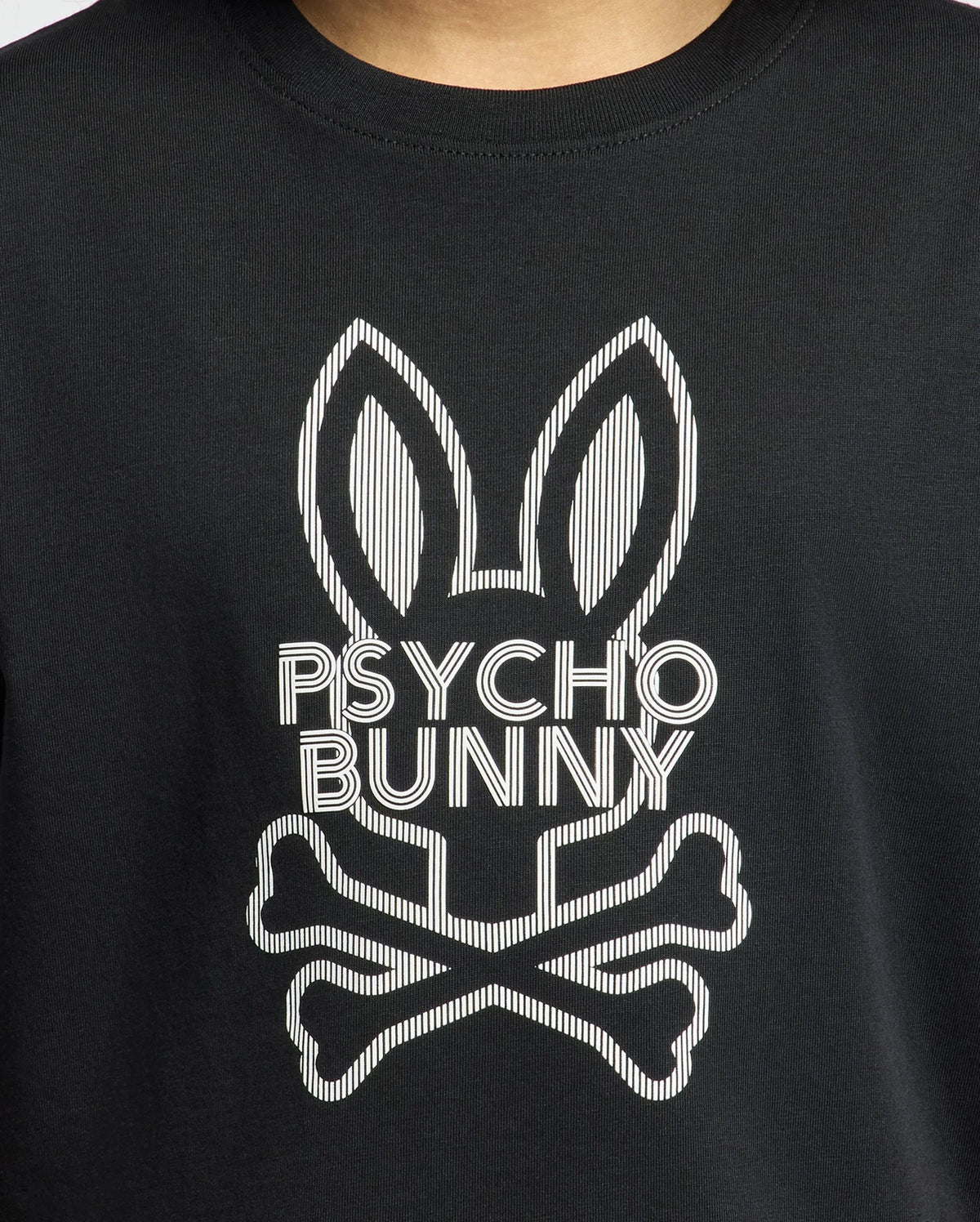The KIDS DUMON GRAPHIC TEE - B0U271E200 by Psycho Bunny provides an up-close look at a black tee made from soft Pima cotton. It showcases a chic bunny logo with elongated ears above the words "PSYCHO BUNNY," accompanied by a crossed bones design underneath, seamlessly combining comfort with an edgy style.
