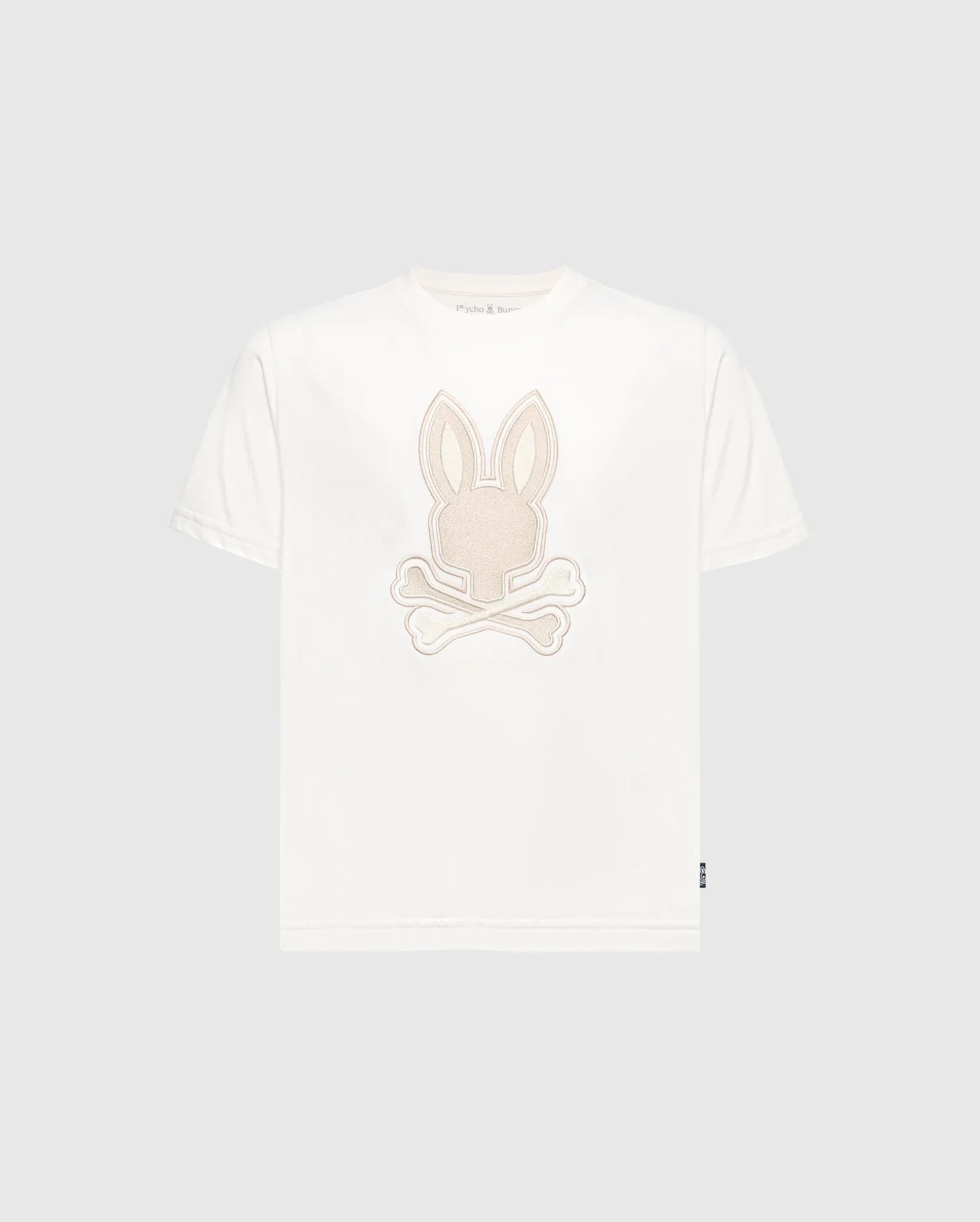 Introducing Psycho Bunny's Kids New Castle Embroidered Graphic Tee (B0U415F200): A white Pima cotton T-shirt showcasing a beige embroidered rabbit's head with crossed bones on the front, creating a striking contrast against its plain gray background.