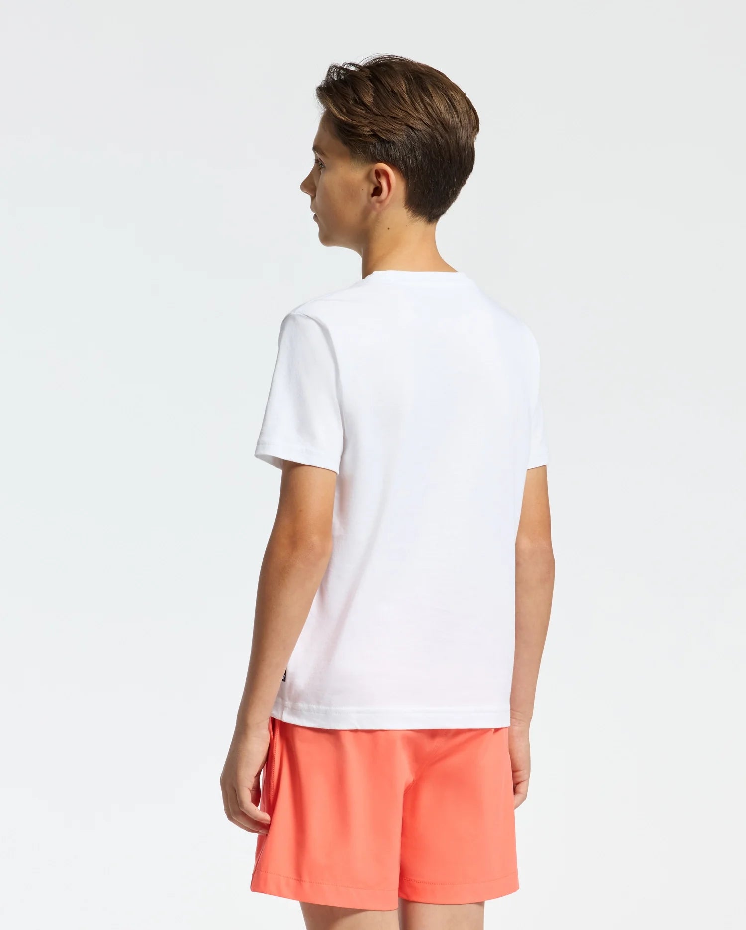 White classic fit jersey t-shirt featuring a subtle black Psycho Bunny tag on the left hem, complemented by vibrant orange relaxed fit athletic shorts.