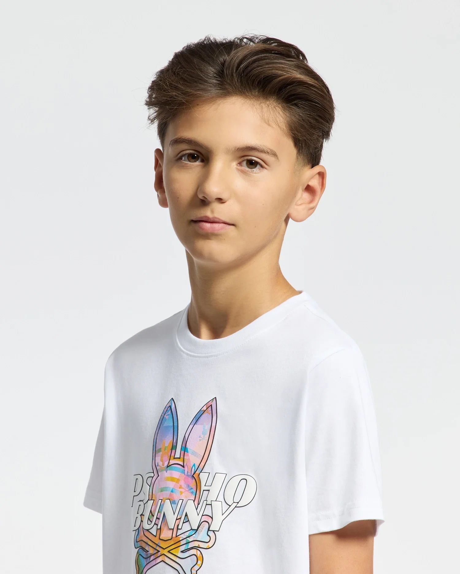 White jersey t-shirt with a classic fit, featuring a large center chest graphic of the iconic Psycho Bunny skull logo in vibrant multi-color pastels, overlaid with black outlined PSYCHO BUNNY text.