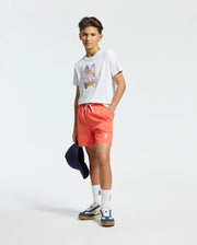White jersey t-shirt with a large, multicolor Psycho Bunny skull graphic on the chest, paired with coral woven shorts featuring a white drawstring and a small embroidered bunny logo on the left thigh.