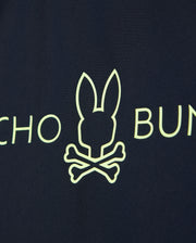 Navy blue fabric of the KIDS SHORT SLEEVE RASH GUARD - B0U558C200 by Psycho Bunny features a neon yellow bunny head above crossed bones with partial text on either side.