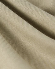 Close-up image of beige fabric with a textured, ribbed surface. The soft and slightly stretchy material, perfect for a Psycho Bunny KIDS KAYDEN FASHION TEE - B0U577C200, presents gentle folds that create depth and dimension. Made from Pima cotton, the knit pattern is smooth and even throughout.
