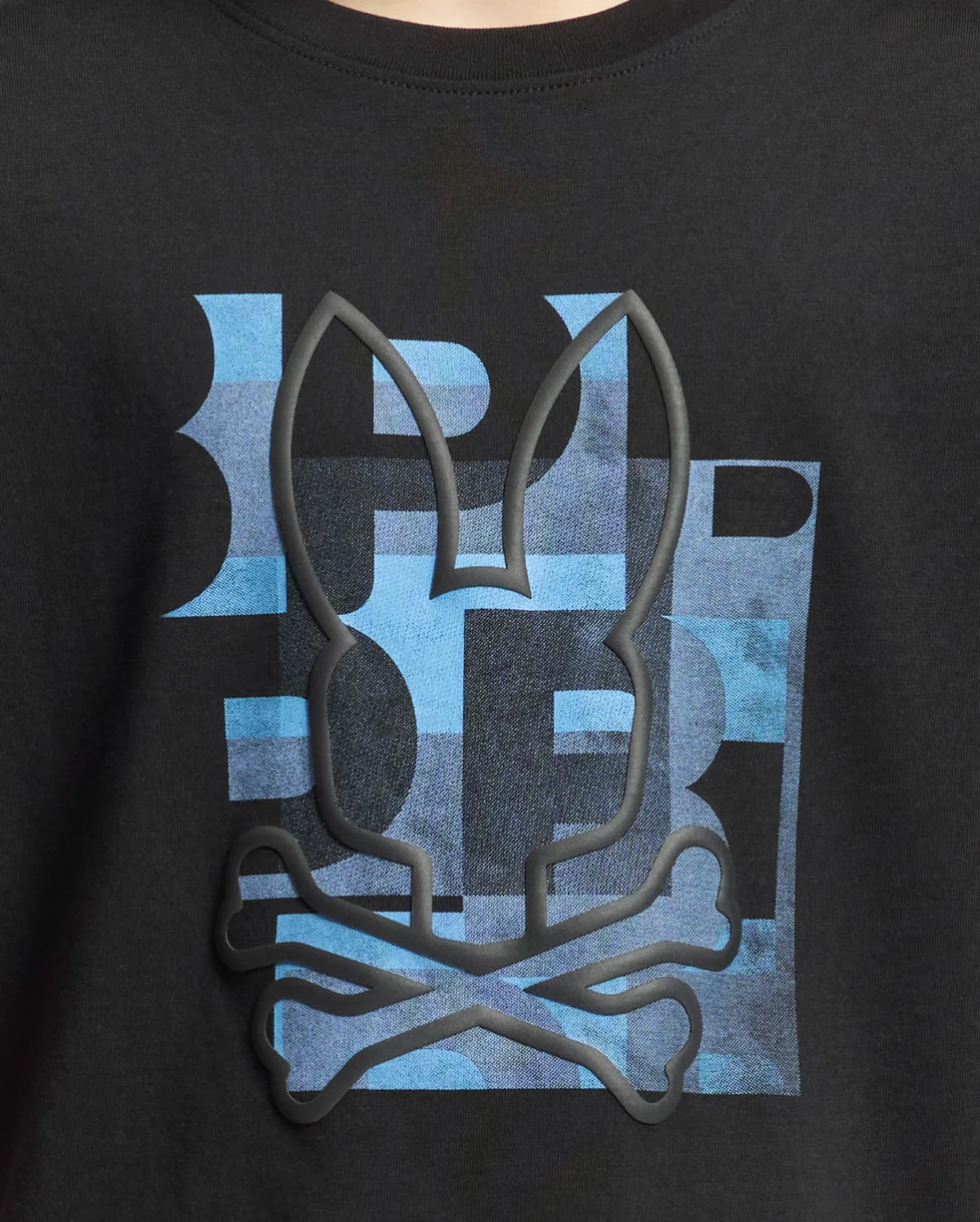 The KIDS ZEALAND GRAPHIC TEE - B0U604F200 by Psycho Bunny features soft Pima cotton with a long-eared bunny logo above crossed bones in rubber texture. Its playful, blue patterned background with abstract letters adds charm.