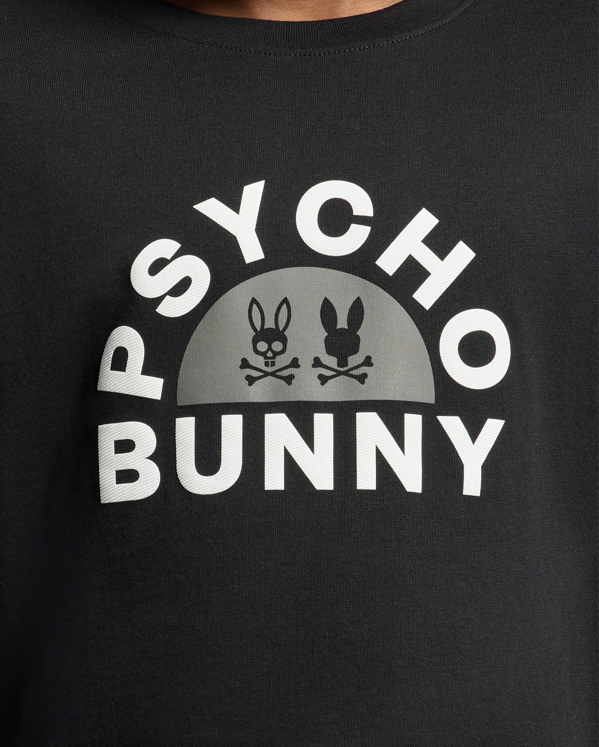 The KIDS GOLDIE GRAPHIC TEE - B0U606F200 from Psycho Bunny is a stylish black tee made of Peruvian Pima cotton, showcasing a bold white "Psycho Bunny" logo and two bunny skulls with crossbones in a semi-circle, perfect for making a statement.