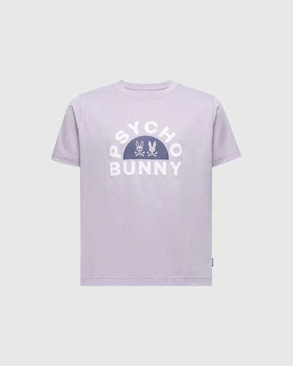 The KIDS GOLDIE GRAPHIC TEE by Psycho Bunny is made of soft Peruvian Pima cotton. The design showcases "PSYCHO BUNNY" in bold white letters, with two small bunny skull icons centered in a semicircle below, all on a lavender background.