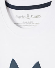 Close-up of a white KIDS HOUSTON GRAPHIC TEE - B0U607C200 tag with the brand "Psycho Bunny" printed above wash instructions and fabric composition, with a hint of the garment's navy detail visible.