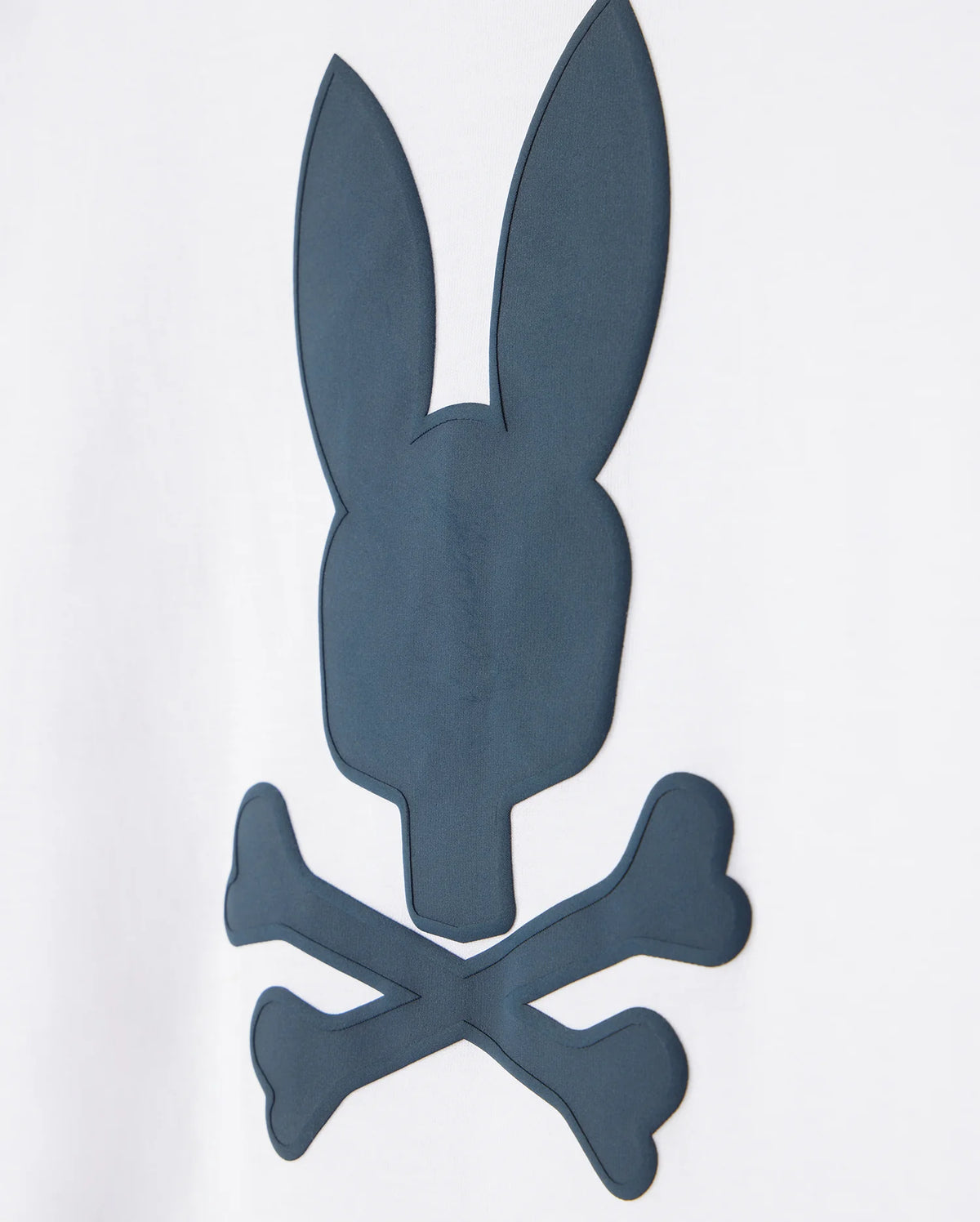 A dark grey silhouette of a stylized skull and crossbones, where the skull is replaced with a rabbit head with elongated ears, embroidered on a Psycho Bunny Pima cotton t-shirt against a plain white background.