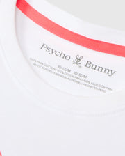 Close-up of a white garment's label, displaying the brand name "Psycho Bunny" along with two stylized bunny ears and skull logo. The label indicates that the KIDS VINCENT GRAPHIC TEE - B0U713D200 is crafted from 100% Pima cotton, sized 10-12/M, and made in Peru with information provided in both English and French.