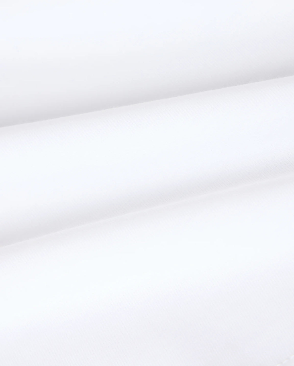 Close-up image of the Kids Vincent Graphic Tee - B0U713D200 by Psycho Bunny, showcasing its smooth, white fabric with subtle diagonal lines and horizontal folds. The texture appears soft and lightweight, reminiscent of the luxurious feel of Pima cotton—perfect for creating unfadable style in children's clothing.