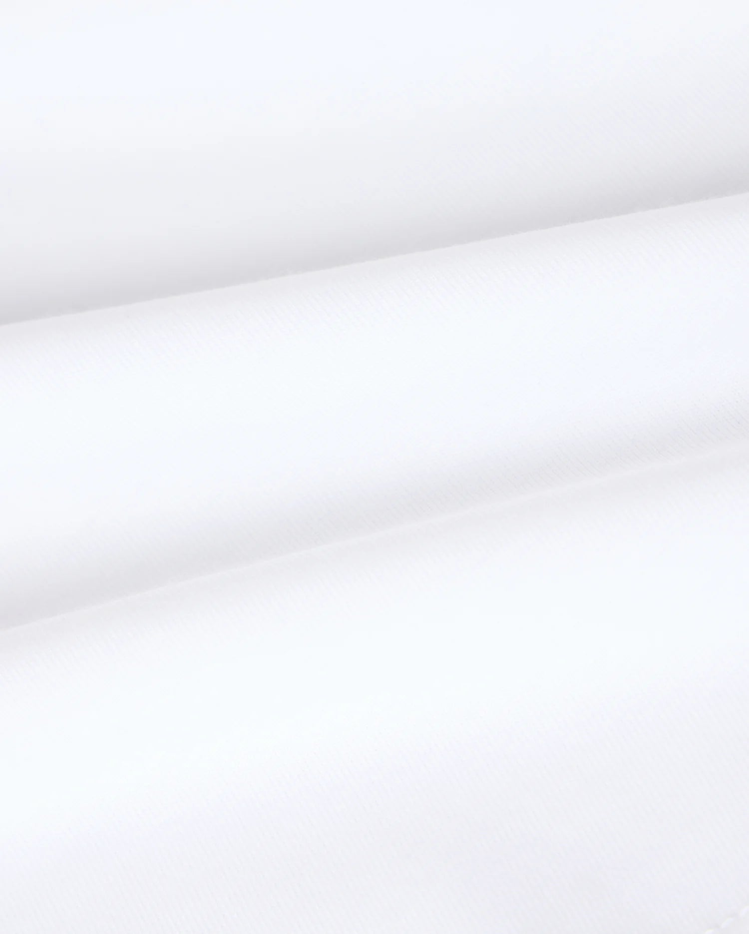 Close-up image of the Kids Vincent Graphic Tee - B0U713D200 by Psycho Bunny, showcasing its smooth, white fabric with subtle diagonal lines and horizontal folds. The texture appears soft and lightweight, reminiscent of the luxurious feel of Pima cotton—perfect for creating unfadable style in children's clothing.