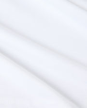 Close-up of smooth white fabric with subtle shadows, featuring a slightly folded surface. Made from Pima cotton, the texture appears soft and light, evoking a sense of simplicity and purity reminiscent of a Psycho Bunny KIDS KINGSTON GRAPHIC TEE - B0U743D200.