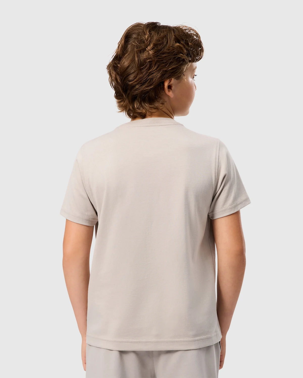 A person with short, curly hair is seen from the back, wearing a light gray Kids Malton Graphic Tee (B0U795D200) made of soft Pima cotton by Psycho Bunny. The background is plain white.