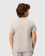 A person with short, curly hair is seen from the back, wearing a light gray Kids Malton Graphic Tee (B0U795D200) made of soft Pima cotton by Psycho Bunny. The background is plain white.
