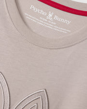 Close-up of a light-colored KIDS MALTON GRAPHIC TEE - B0U795D200 by Psycho Bunny, crafted from soft Pima cotton, featuring the brand's label and size details printed inside the collar. The collar is accented with a red lining, and part of an embroidered design is visible near the bottom left of the image.