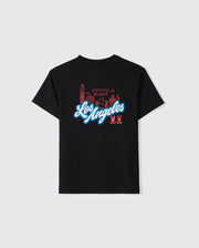 The KIDS LOS ANGELES CITY TEE - B0U861A2PC by Psycho Bunny features a luxurious Peruvian Pima cotton black T-shirt with "Los Angeles" boldly printed in white and blue font across the back. Above the text, decorative red line drawings of landmarks and symbols accompanied by "Psycho Bunny" add extra flair. Additionally, two small bunny logos embellish the bottom right corner.