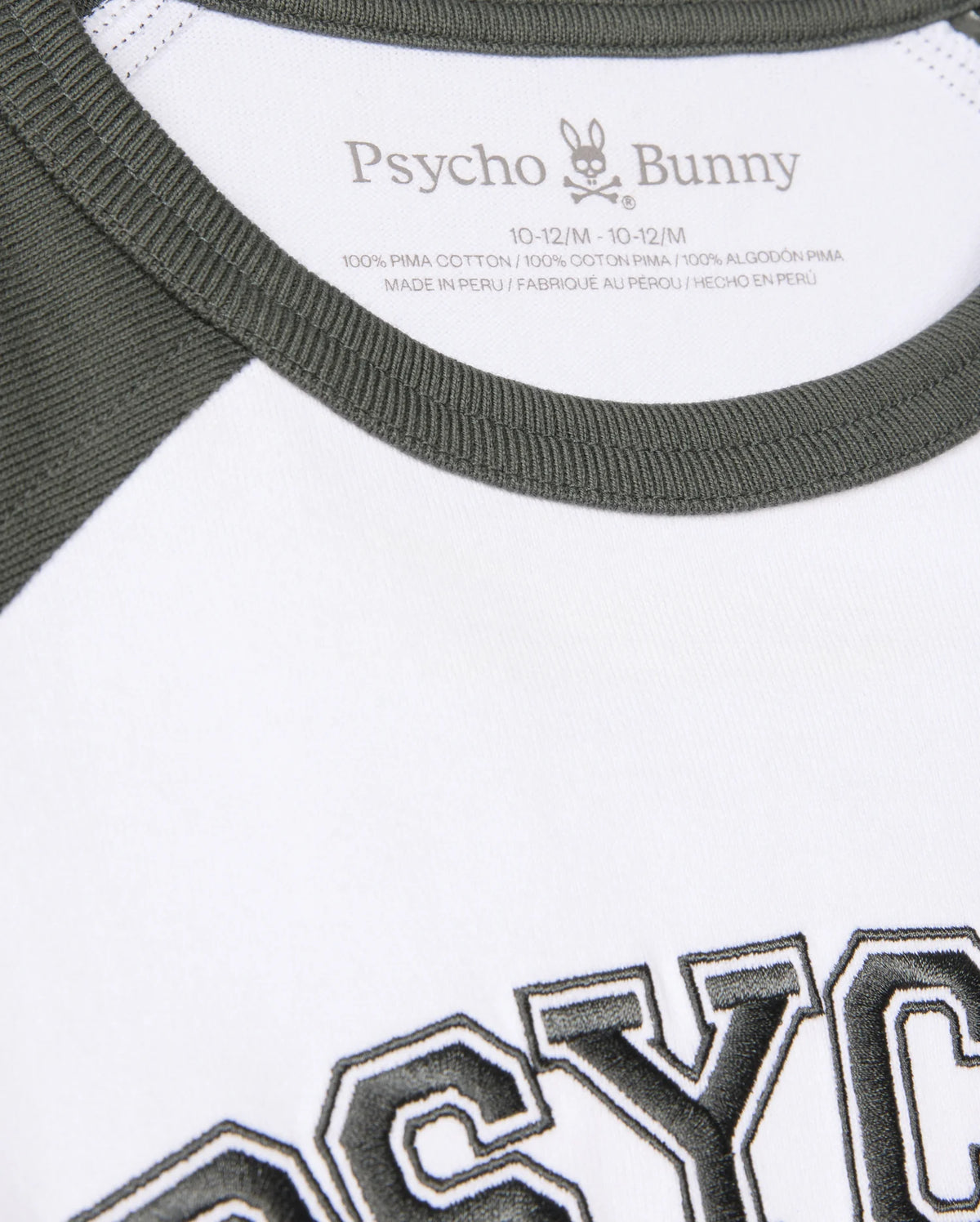 Close-up of a Kids London Raglan Graphic Tee (B0U896D200) by Psycho Bunny, featuring green neckline and sleeves, "PSYCHO" in bold black, and crafted from 100% Pima cotton in Peru for style and comfort.