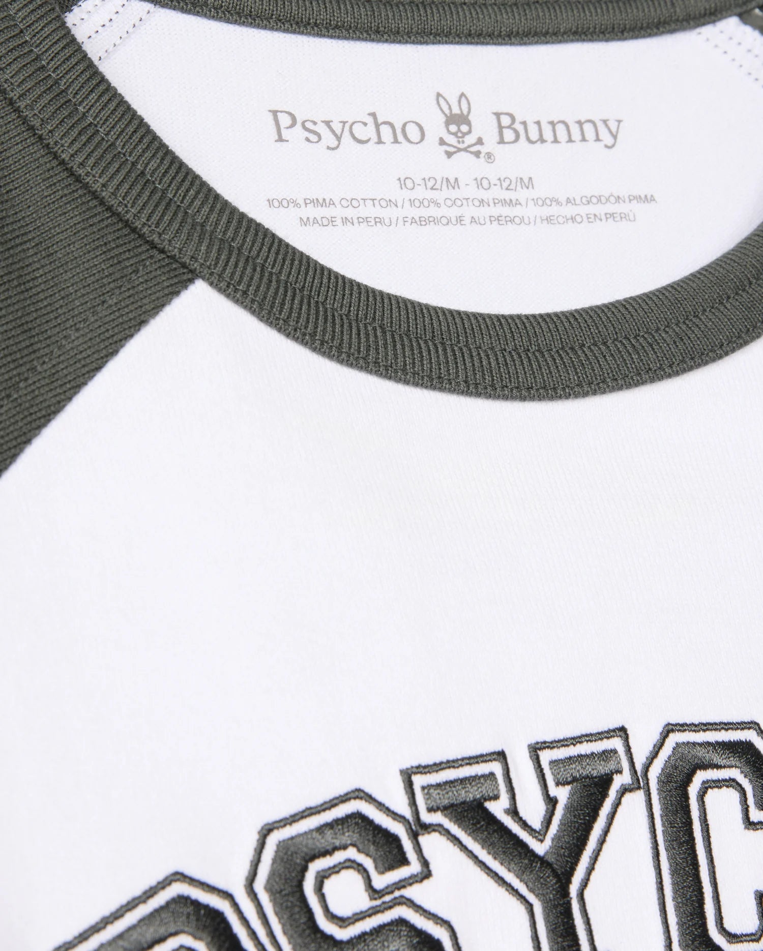 Close-up of a Kids London Raglan Graphic Tee (B0U896D200) by Psycho Bunny, featuring green neckline and sleeves, "PSYCHO" in bold black, and crafted from 100% Pima cotton in Peru for style and comfort.
