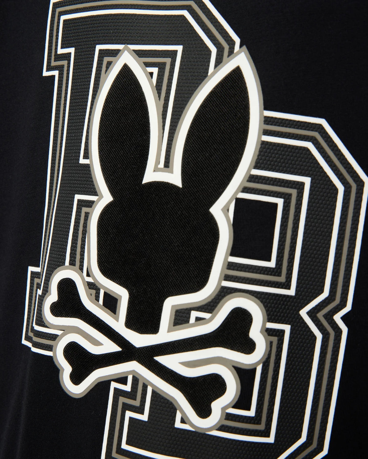 The KIDS ZACK GRAPHIC TEE - B0U897D200 from Psycho Bunny features a black and white design with a Psycho Bunny silhouette above two crossed bones, evoking a skull and crossbones theme, accompanied by a stylized letter "B" in the background. Made from soft Pima cotton, this tee is a striking statement piece.
