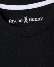 Close-up of the KIDS ZACK GRAPHIC TEE (B0U897D200) from Psycho Bunny, featuring a black Pima cotton shirt collar with the brand's iconic bunny head and crossbones logo, accented by white stitching along the neckline.