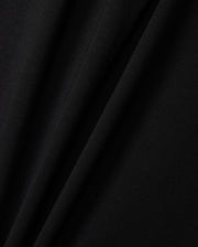 Close-up of a black Pima cotton fabric exhibiting gentle folds and a smooth texture, highlighting the delicate interplay of light and shadow across the material, reminiscent of a finely crafted KIDS ZACK GRAPHIC TEE by Psycho Bunny.