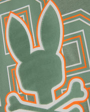 The KIDS ZACK GRAPHIC TEE - B0U897D200 by Psycho Bunny features a green pattern that highlights the iconic Psycho Bunny head with crossbones underneath. Accented with orange and white lines, its geometric background is crafted from soft Pima cotton, combining bold style with comfort.