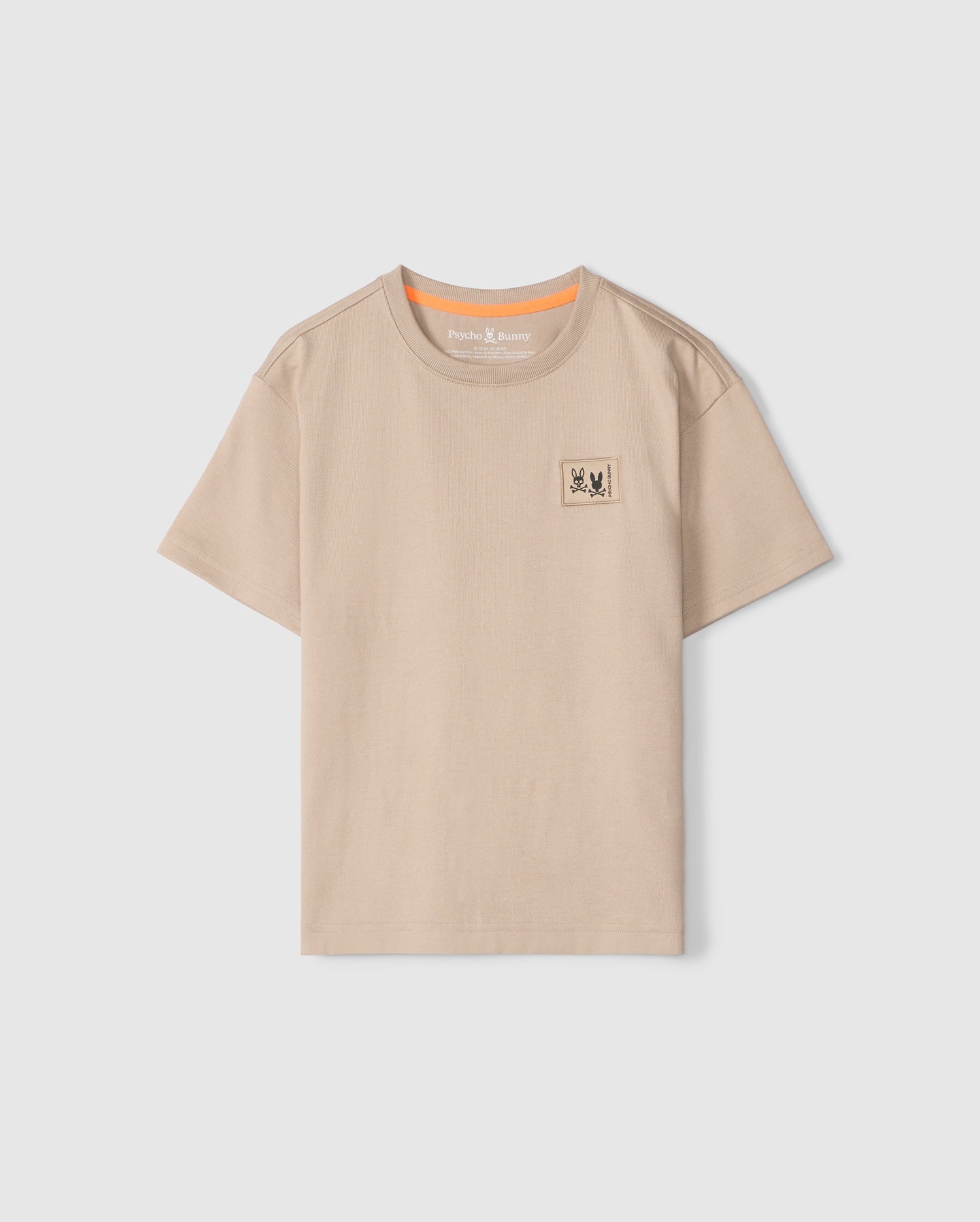 The KIDS MONROE HEAVY WEIGHT RELAXED FIT TEE by Psycho Bunny is made from soft Pima cotton, featuring a beige hue, short sleeves, and a round neckline. It includes a small printed patch with two stylized animals on the upper left chest and an orange accent inside the collar.