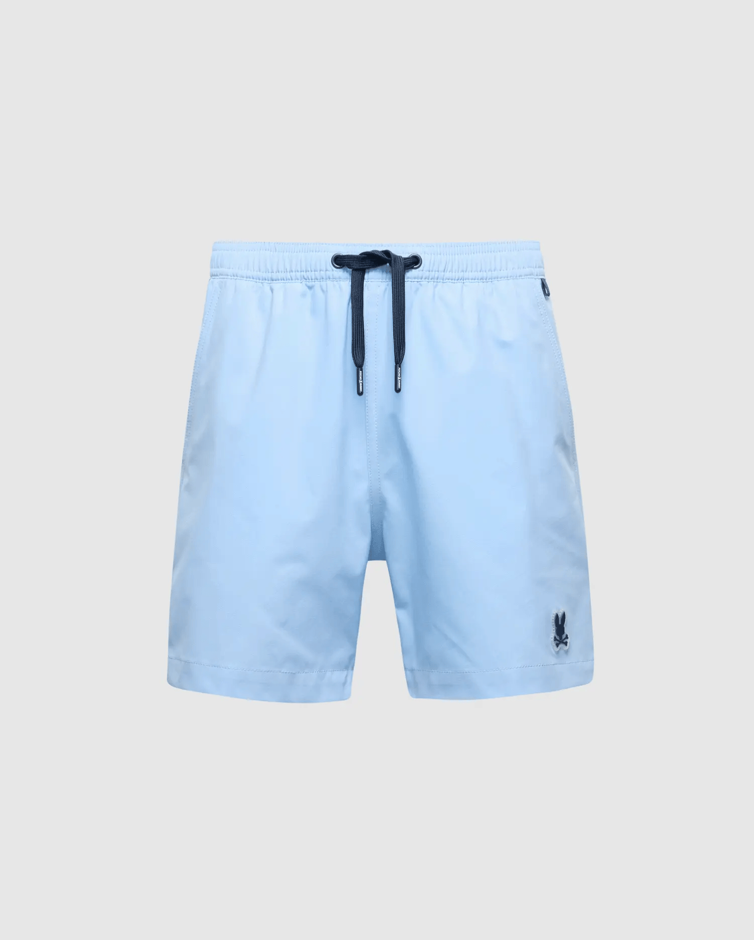 Psycho Bunny's KIDS SAMOS HYDROCHROMIC PRINTED SWIM TRUNK - B0W453F200 features light blue fabric with a dark drawstring waistband, hydrochromic technology, and a small embroidered logo on the lower left side, offering a stylish contrast against any plain gray background.