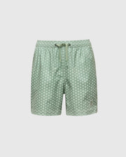 The KIDS BENDIGO PRINTED SWIM TRUNK - B0W619F200 by Psycho Bunny features light green swim shorts with white polka dots, crafted from quick-dry fabric. They have a drawstring waistband and are perfect for summer. Stored in a waterproof bag against a plain white background.