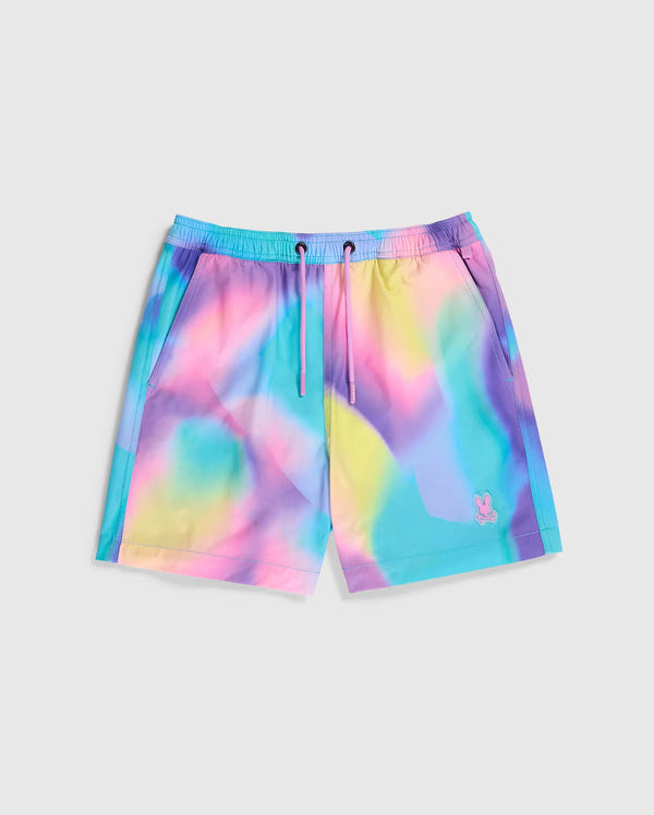Colorful boys' swimwear featuring a multicolor design with a psychedelic tie-dye pattern in pastel shades of blue, pink, yellow, and purple. The quick-dry KIDS TYLER PRINT SWIM TRUNK - B0W620C200 by Psycho Bunny has an elastic waistband with a drawstring and a small embroidered logo of a bunny near the hem. The background is plain gray.
