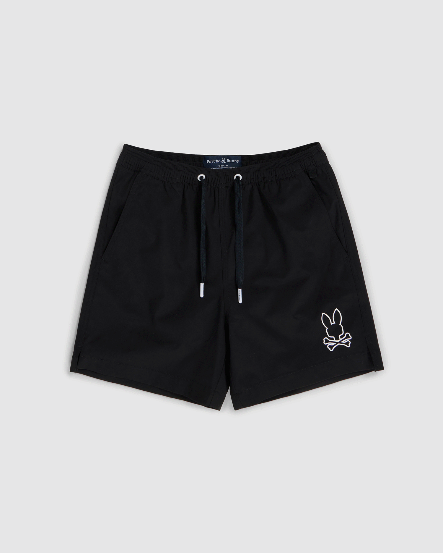 Black shorts featuring a white outline of a bunny with crossbones on the bottom right corner. Made from quick-dry material, these shorts have an elastic waistband with a black drawstring and two side pockets. Ideal for summer, the **KIDS PARKER HYDROCHROMIC SWIM TRUNK - B0W646C200** design by **Psycho Bunny** blends style and function against a light gray background.
