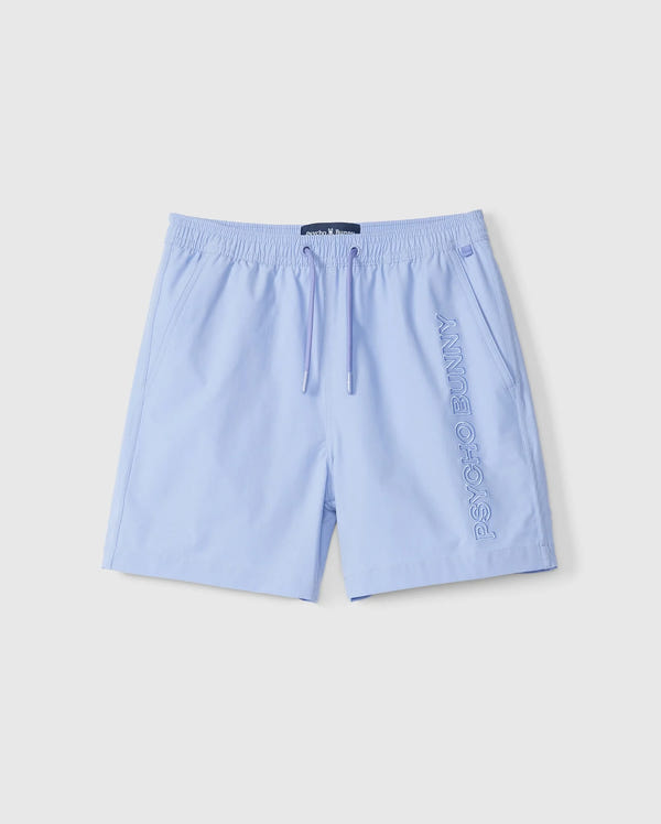 Light blue quick-dry KIDS MELVIN SWIM TRUNK by Psycho Bunny, featuring an elastic waistband and drawstring. The brand name is embroidered vertically on the left leg. Suitable for leisure or sports, these casual swim trunks provide comfort and functionality.