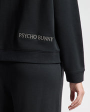 A person is wearing the WOMENS ALEXANDER SWEATSHIRT - B2S156E200 by Psycho Bunny, featuring a black cotton blend design. "PSYCHO BUNNY" is embroidered on the back near the waist, and their hand highlights the intricate Lurex Bunny detail. The emphasis is on this stylish clothing accent.