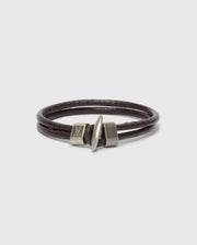 The Psycho Bunny MEN'S LEATHER BRACELET - B6A369E200 is a stylish double-wrap piece with a sleek cylindrical metal clasp, elegantly presented on a plain white background. The clasp adds modern flair to the rich dark brown leather, perfect for any style-conscious individual.