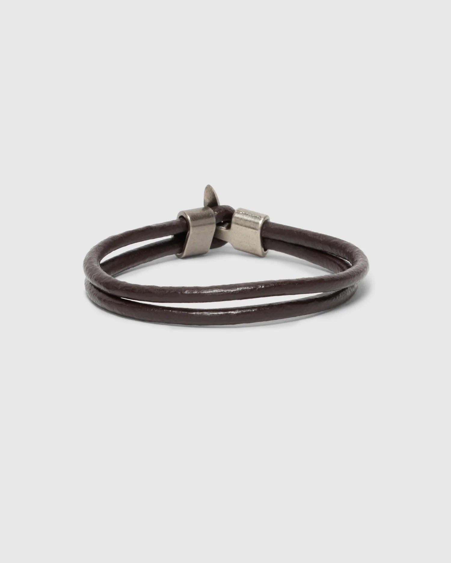 The Psycho Bunny Men's Leather Bracelet - B6A369E200 showcases a double band in brown leather with sleek metallic clasps. Perfect for a modern fit, it is elegantly presented on a plain gray background, emphasizing its timeless appeal.