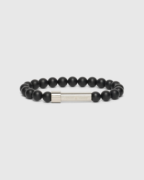 The Psycho Bunny MEN'S BEAD BRACELET - B6A370E200 features a high-quality beaded design, complete with a silver clasp engraved with text. Arranged in a circular shape on a light gray background, it makes the perfect fashion accessory.