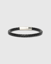 The Psycho Bunny Men's Braided Leather Bracelet (B6A371E200) in sleek black, features a silver clasp and combines durability with style against a neutral backdrop.