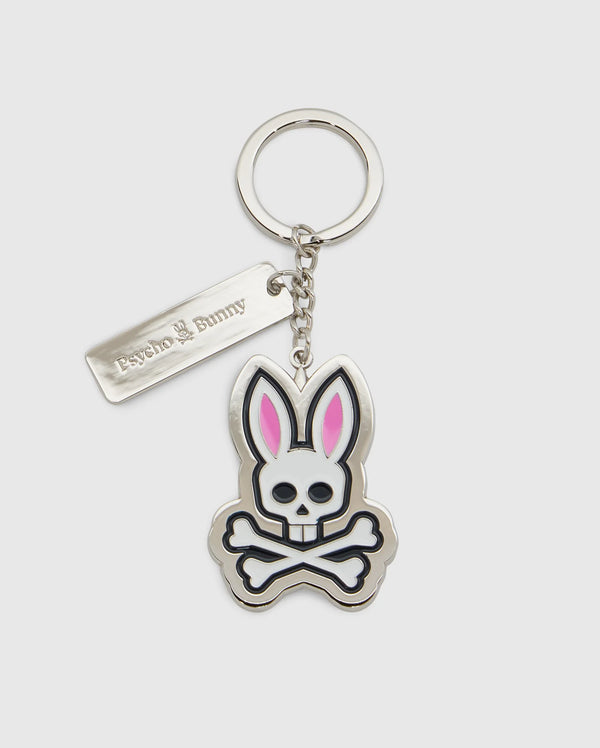 Introducing the CLASSIC BUNNY KEYCHAIN - B6A372E200 from Psycho Bunny, a fashionable metal accessory showcasing a cartoon bunny skull and crossbones design with distinctive pink ears. This practical everyday keychain features a sleek rectangular tag engraved with "Psycho Bunny." Complemented by a silver-colored chain and keyring, it adds a chic touch to your essentials.