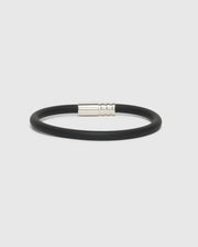 A sleek and modern silicone bracelet featuring a black band and a silver magnetic clasp, designed by Psycho Bunny, showcased against a plain white background.