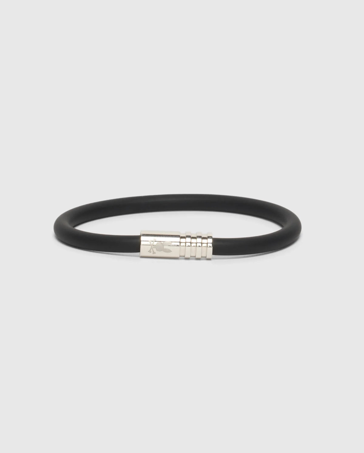 A stylish silicone bracelet in black, complete with a simple silver clasp with subtle engravings, adding an elegant touch. Displayed on a white background, this accessory is known as the MEN'S ROUND SILICONE BRACELET - B6A386E200 by Psycho Bunny.
