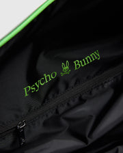 The black MENS DUFFLE BAG - B6A472F200 by Psycho Bunny features a zippered pocket inside, adorned with green "Psycho Bunny" text and a bunny skull logo. Its smooth, slightly shiny material is ideal for stylish packing.