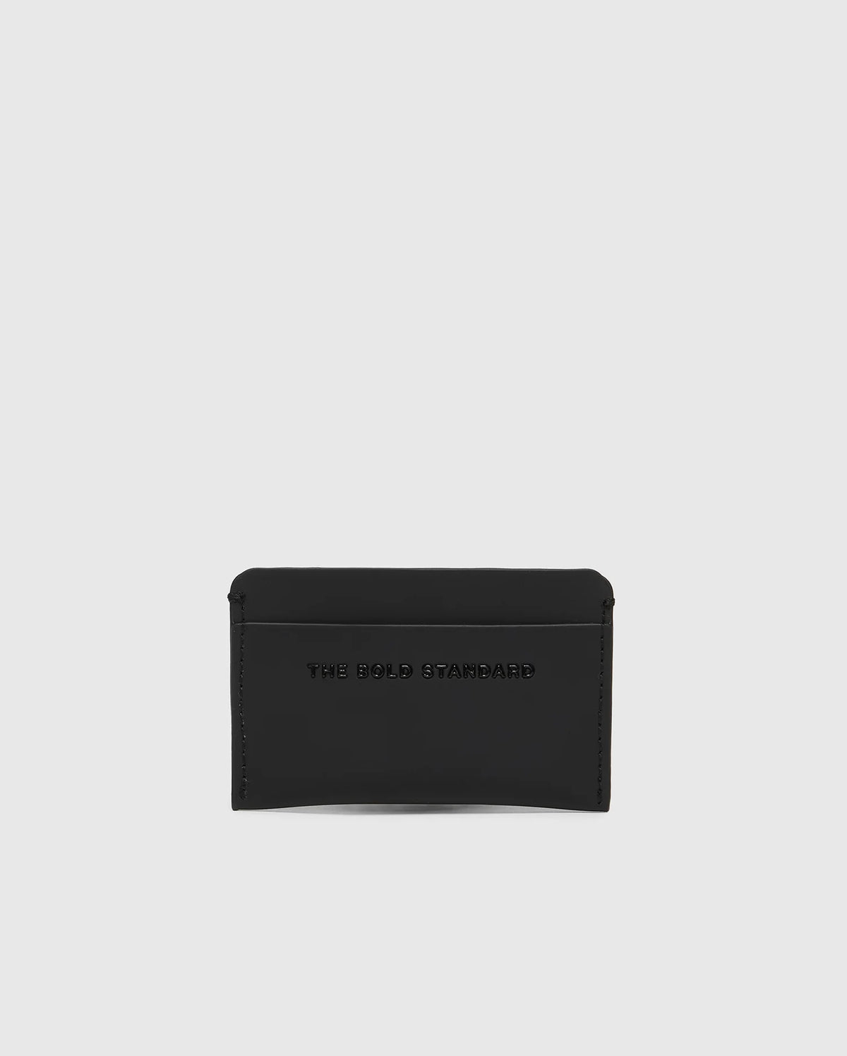 The Psycho Bunny MENS RUBBERIZED CARD CASE - B6A473F200, shown in black against a white background, offers peace of mind with its sleek design. Embossed with "THE BOLD STANDARD," this minimalist card case keeps your essentials safe.