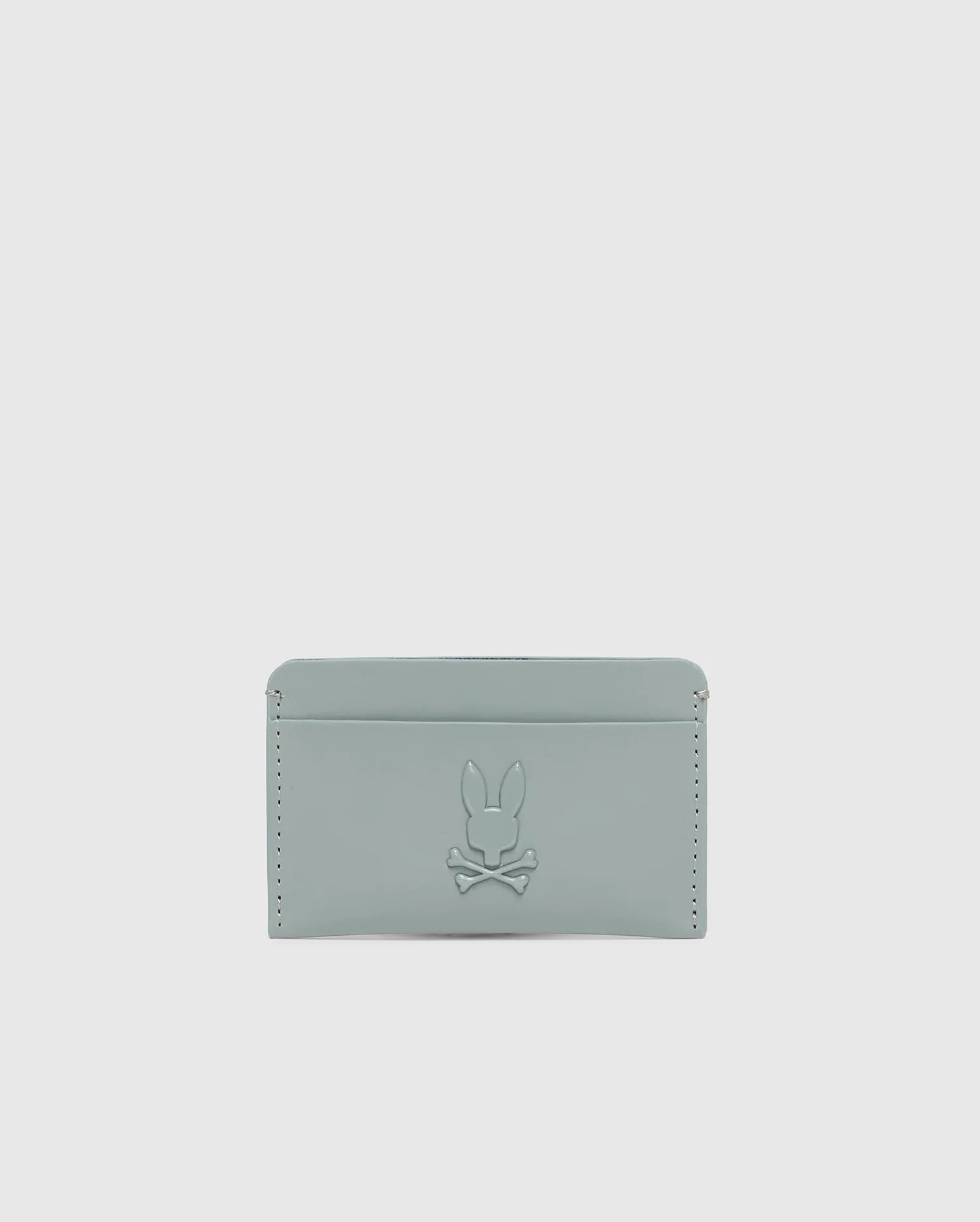 The "MENS RUBBERIZED CARD CASE - B6A473F200" by Psycho Bunny is a minimalist, light gray wallet featuring a subtle rabbit and crossbones embossment and edge stitch details for secure storage.