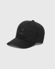 The Psycho Bunny MENS NEW CASTLE GRAPHIC BASEBALL CAP - B6A547F200 is a black cotton twill cap with an animal-like logo, curved brim, and visible stitching. It features an adjustable back strap on a plain light gray background.